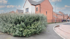 A residential area with houses, a paved road, and a well-maintained hedge. - Quiet and Lovely 3-bed house parking and garden (Wolverhampton)