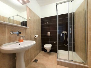 Ein modernes Badezimmer mit Duschkabine aus Glas, einem weißen Waschbecken und einer Toilette.