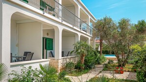 A two-story building with balconies, outdoor seating, and a garden with plants and a pathway. - Katarina 3 by Interhome (Šibenik)