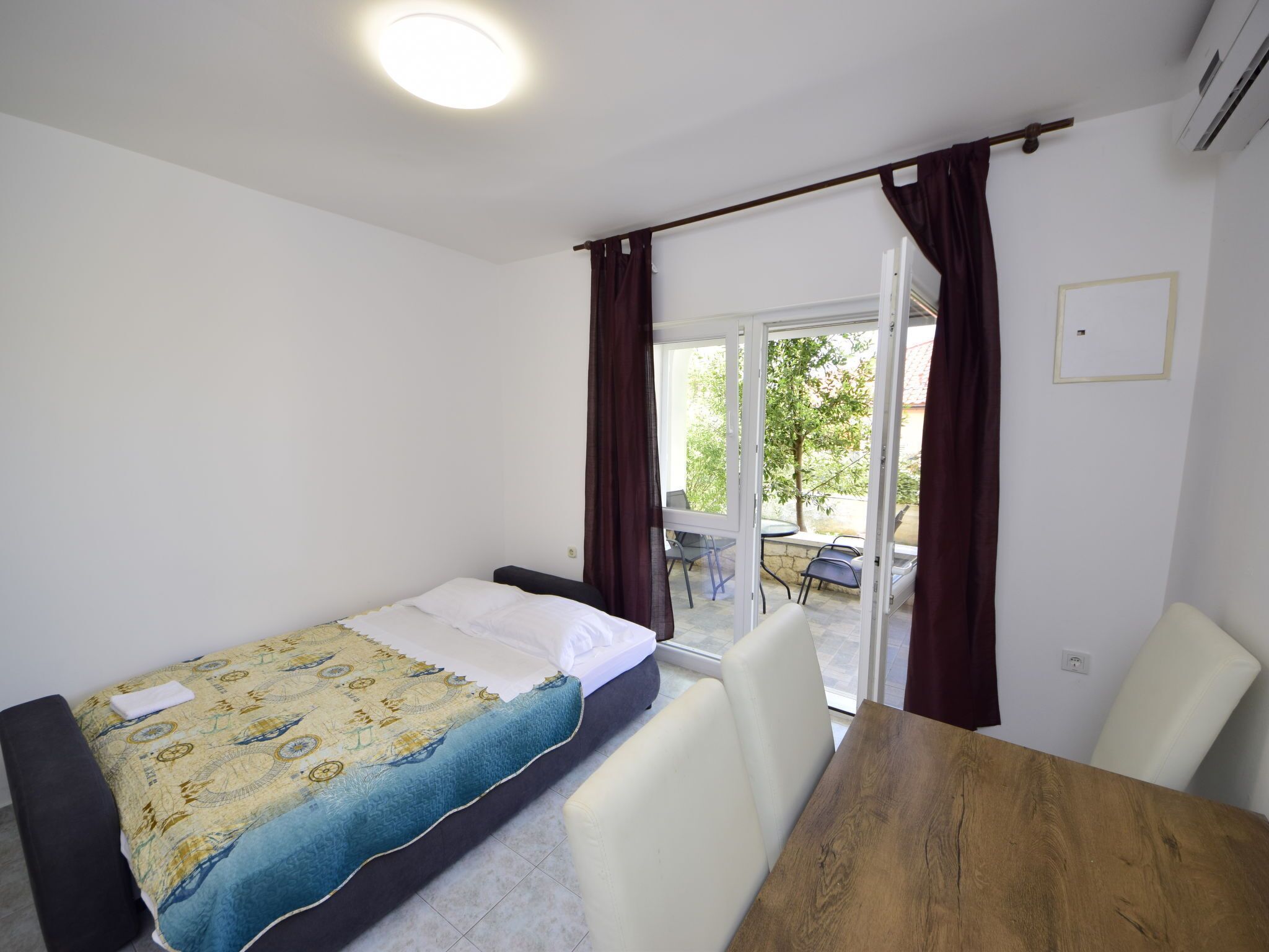 Un dormitorio con una cama, una mesa de madera y vistas al exterior a través de un ventanal corredero.