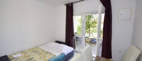 Un dormitorio con una cama, una mesa de madera y vistas al exterior a través de un ventanal corredero.