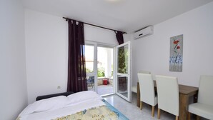 A bedroom with a bed, a dining table with chairs, a sliding glass door leading to an outdoor area, and an air conditioning unit on the wall. - Katarina 3 by Interhome (Šibenik)