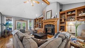 Un salon chaleureux avec une cheminée, des étagères en bois et des sièges confortables.
