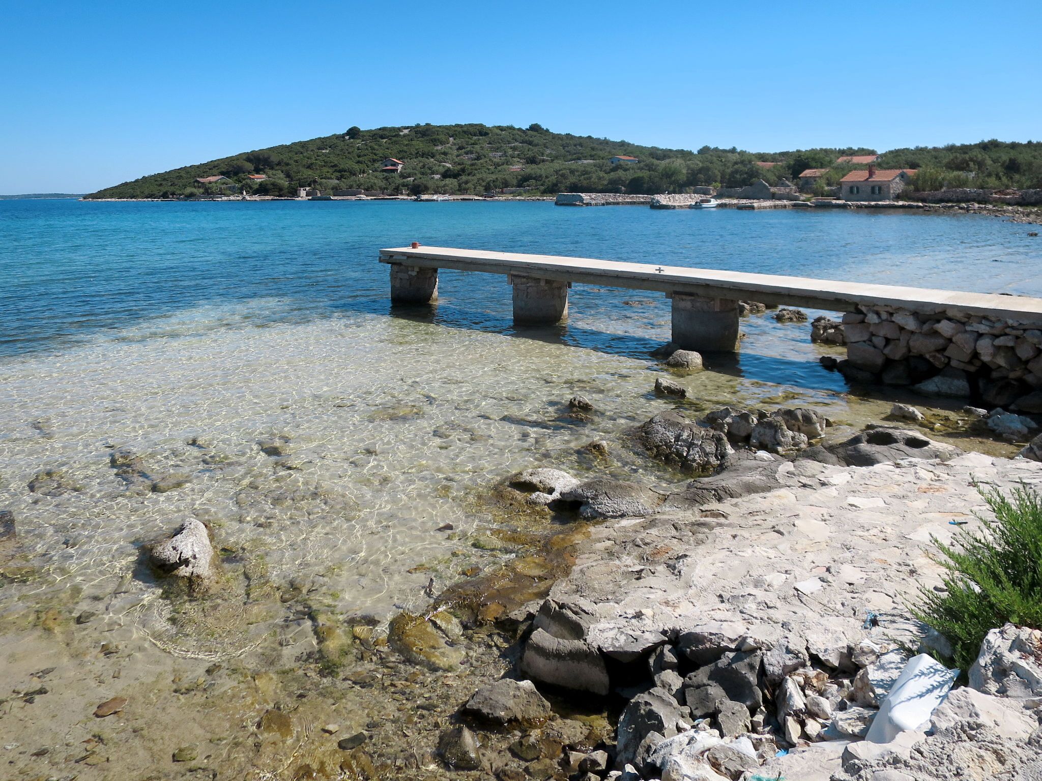A clear coastal area with a stone pier extending into the water, surrounded by rocks and clear shallow water. - Kalebica by Interhome (Pašman/Pašman)