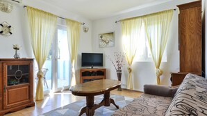 Ein Wohnzimmer mit einem Holzkasten, einem Fernseher, einer Couch und einem gemusterten Teppich.