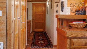 Un corridoio in legno con un tappeto decorato, mobili contenitori in legno e una porta che dà su un'altra stanza.