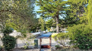 A stone pathway leading to a gated entrance surrounded by lush greenery and trees. - Gottwald by Interhome (Starigrad-Paklenica)