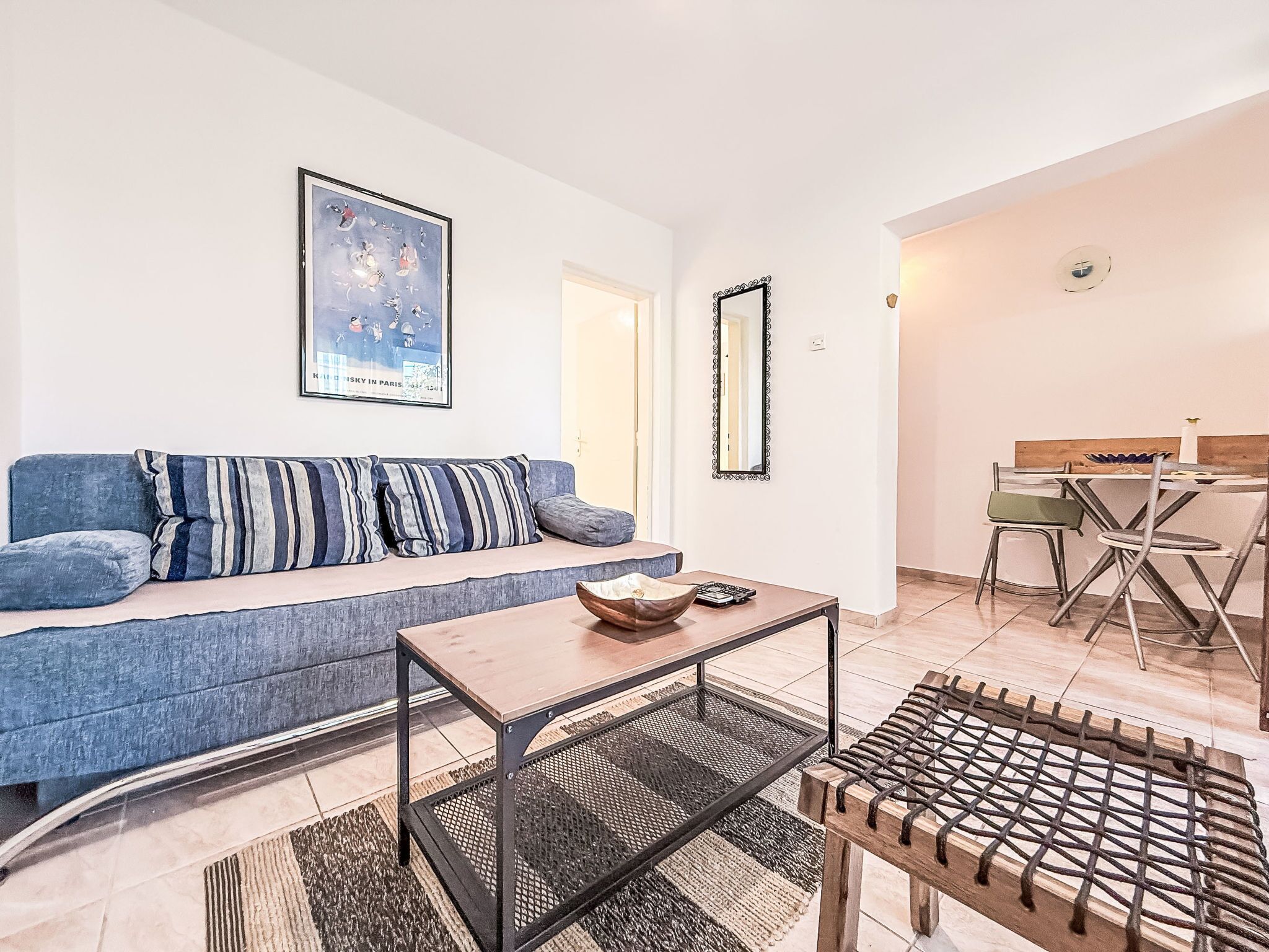 A living room with a sofa, a coffee table, and a dining area with chairs and a table.