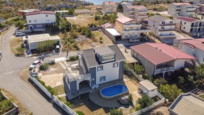 A residential area with multiple two-story houses, a swimming pool, and a view of the sea. - Apartment Golic by Interhome (Karlobag)