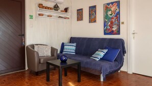 A living room with a sofa, armchair, and coffee table. There are shelves with decorative items and a painting on the wall. - Apartment Popara by Interhome (Crikvenica/Jadranovo)