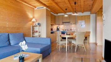 Ein gemütliches Wohnzimmer mit einem blauen Sofa, einem Holztisch und einem Essbereich mit Tisch und Stühlen.