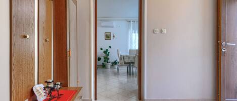 Un corridoio con una porta in legno, un tappetino rosso e un tavolino con oggetti decorativi.