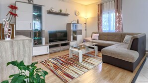 A modern living room with a flat-screen TV, a sofa, a coffee table, and a patterned rug. - Apartment Cekić by Interhome (Rovinj)