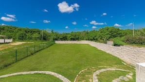 A grassy area with a stone wall and a green fence.