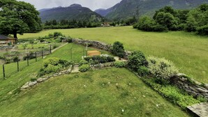 A rural landscape with a stone wall, a wooden bench, and a house in the distance.