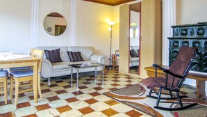 A living room with a checkered floor, a sofa, a coffee table, a rocking chair, a dining table with chairs, a mirror, and a lamp.
