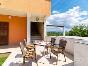 Relax on the patio with a table and four comfortable chairs, surrounded by lush trees and majestic mountains.