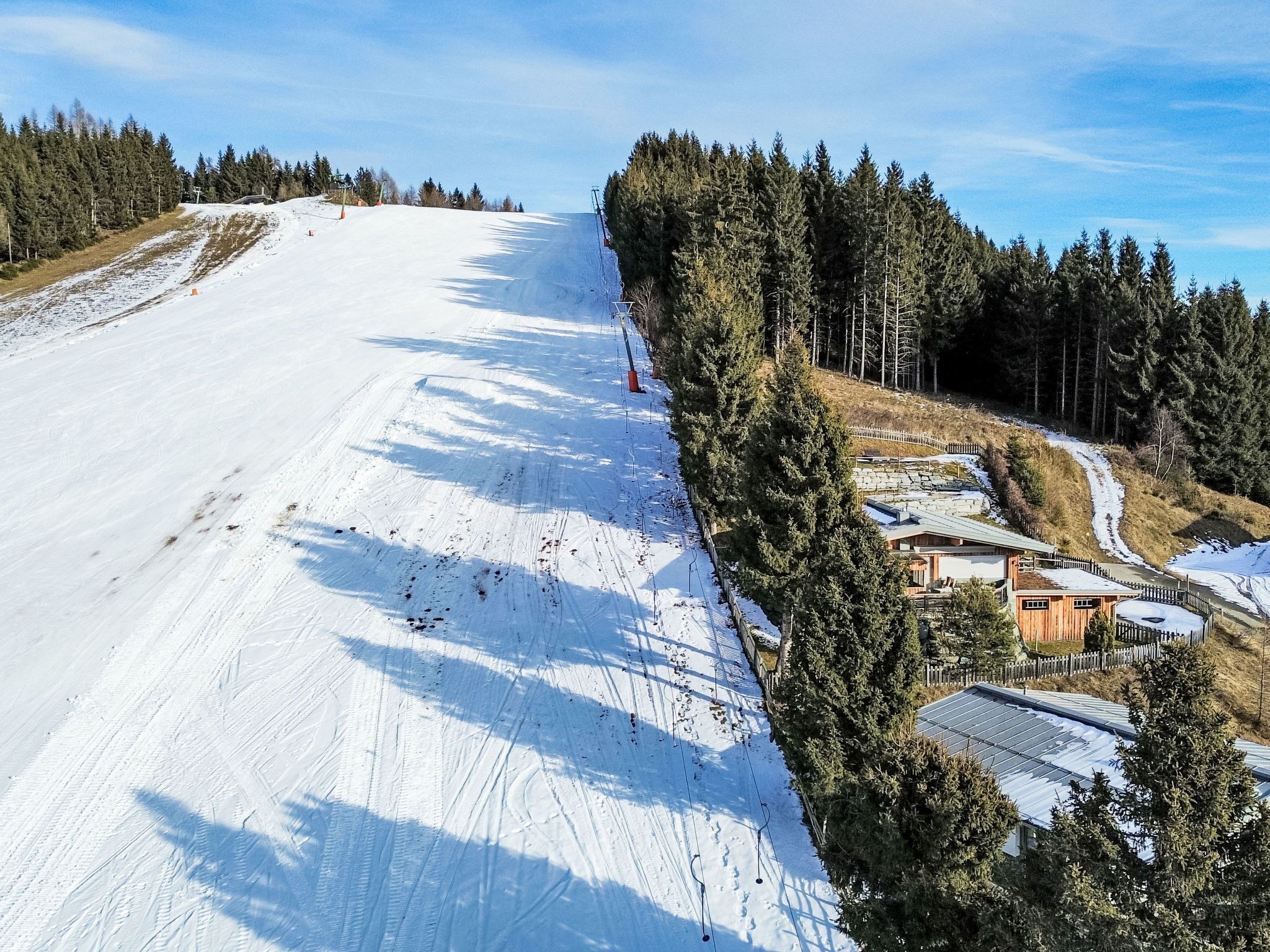 Pista de esquí con una cabaña de madera y árboles circundantes.