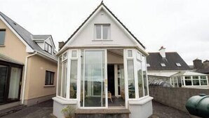 Une maison avec un toit à pignon, une baie vitrée et un petit porche.