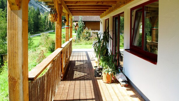 Una terraza de madera con vistas a un paisaje verde y un edificio al fondo.