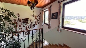 A staircase with a wooden handrail, a wall-mounted deer head decoration, and a window with curtains. - Apartment Moser by Interhome (Stein an der Enns)