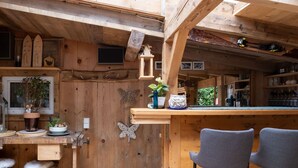 A rustic wooden interior with a bar area, wooden stools, and a shelf with various items. - Alpenchalet Silbertal by Interhome (Silbertal)