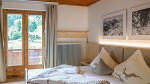 A bedroom with a bed, a window, a radiator, and two framed pictures on the wall. - Alpenchalet Silbertal by Interhome (Silbertal)