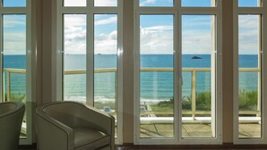 A room with a large window overlooking the ocean, a sofa, and a small table with a magazine. - Reine Marine- T2 SUD by Interhome (Saint Malo)