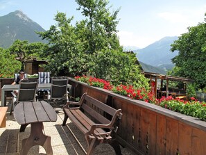 An outdoor patio with wooden furniture, a Coca-Cola sign, and a view of mountains. - Apartment Anich by Interhome (Imst)