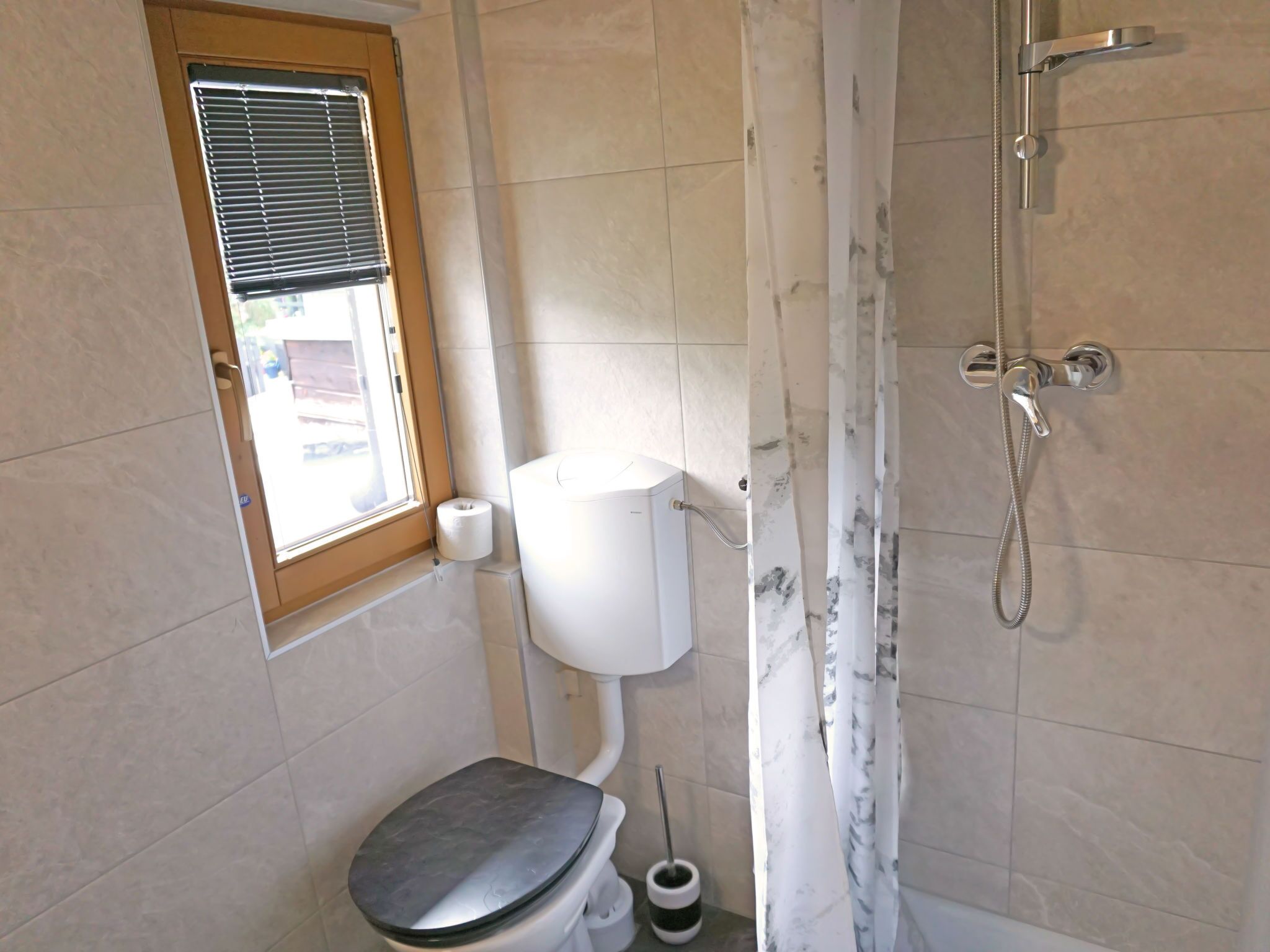 Ein Badezimmer mit Toilette, Dusche und Fenster.