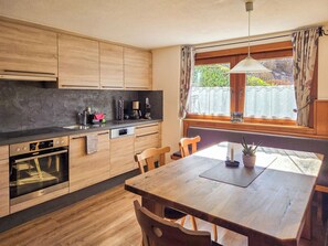 A modern kitchen with wooden cabinets, a built-in oven, and a dining area with a wooden table and chairs. - Vacation home Egger by Interhome (Zell am Ziller)