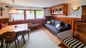 A cozy room with a wooden bench, a dining table, and a sofa.