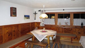 A cozy room with wooden benches and a table, a clock on the wall, and a window with curtains.