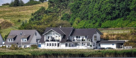 A coastal property with multiple houses, a dock, and a hill with dense greenery in the background.