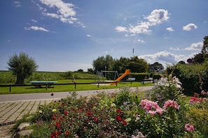 A park with a playground, picnic table, and flower beds.