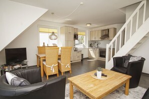 A modern apartment with a dining area, kitchen, living room, and a staircase.