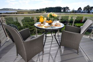 A round table with wicker chairs on an outdoor deck, overlooking a scenic landscape. - Chic vacation apartment with sea view - rügenreif Holiday apartment no. 02 - rügenreif (Mönchgut)