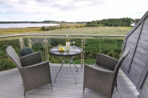 A balcony with wicker chairs and a table, overlooking a lake and fields. - Chic vacation apartment with sea view - rügenreif Holiday apartment no. 03 - rügenreif (Mönchgut)