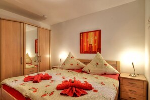 A hotel room with a bed, a wardrobe, a nightstand, and a painting on the wall. - Chic vacation apartment with sea view - rügenreif Holiday apartment no. 03 - rügenreif (Mönchgut)