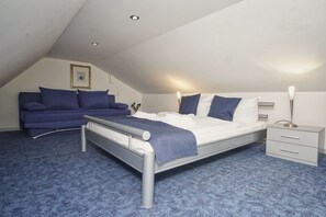 Ein Schlafzimmer mit einem Bett, Nachttischen, einem Sofa und einem Bild an der Wand.