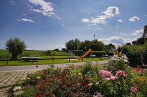 Ein Park mit einem Spielplatz, einem Picknicktisch und Blumenbeeten.