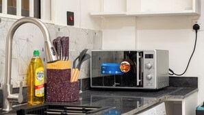 A kitchen with a toaster oven displaying a cooking image, a bottle of oil, and kitchen utensils.