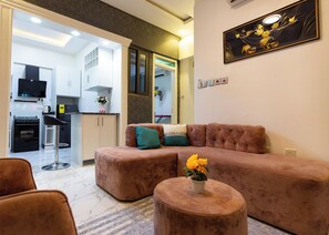 Een moderne woonkamer met een modulaire bank, een ronde salontafel en een keuken op de achtergrond.