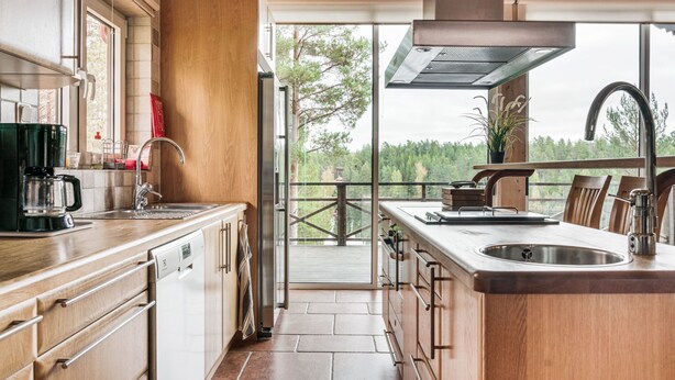 Una cocina moderna con una isla grande, electrodomésticos de acero inoxidable y vistas al exterior.