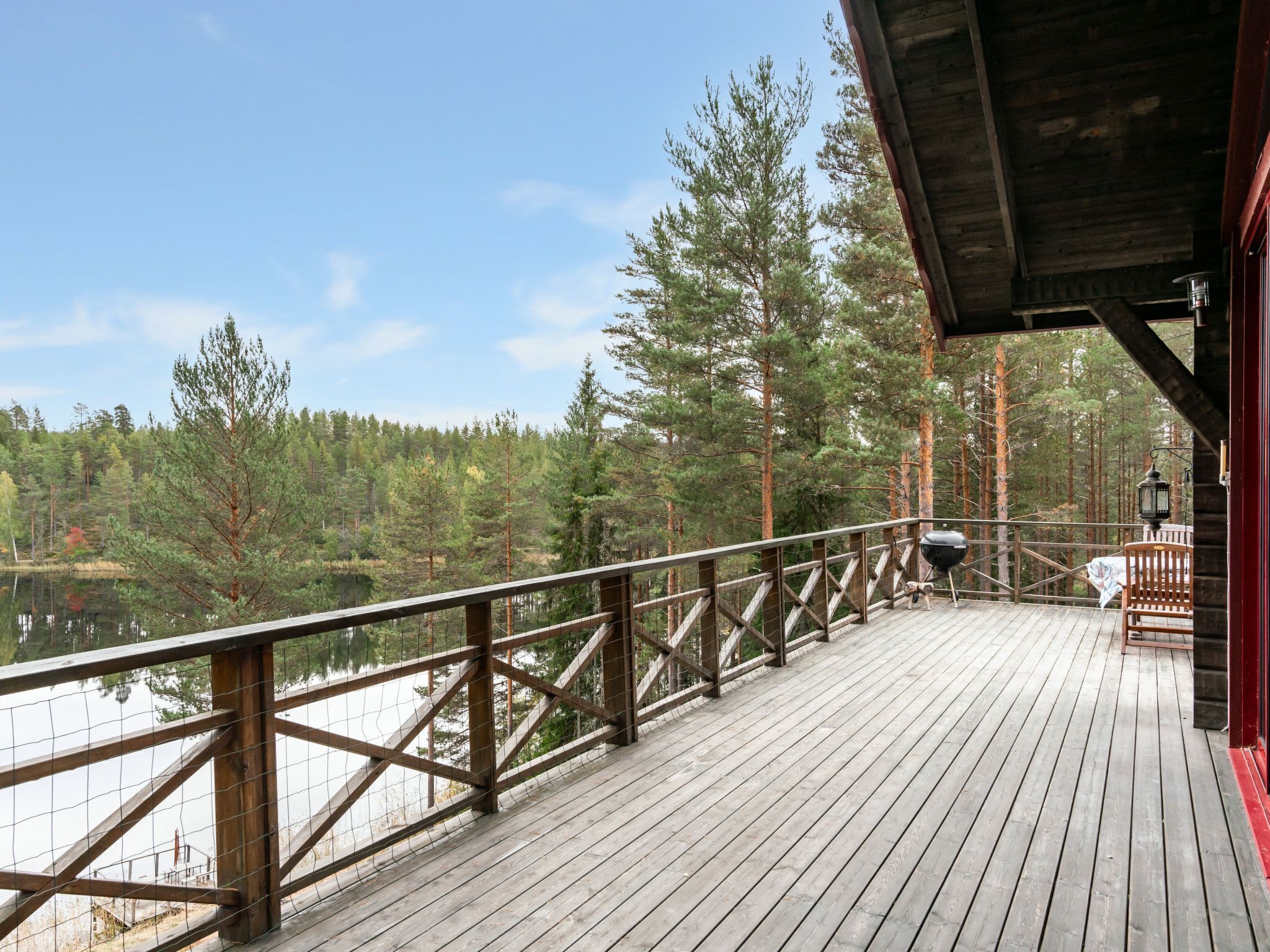 Une terrasse en bois avec une rambarde donnant sur un lac et une forêt.
