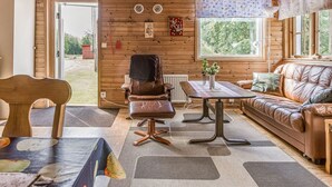 A cozy cabin interior with a wooden ceiling, a leather sofa, a dining table, and a chair. - Tingsmåla by Interhome (Tingsryd)