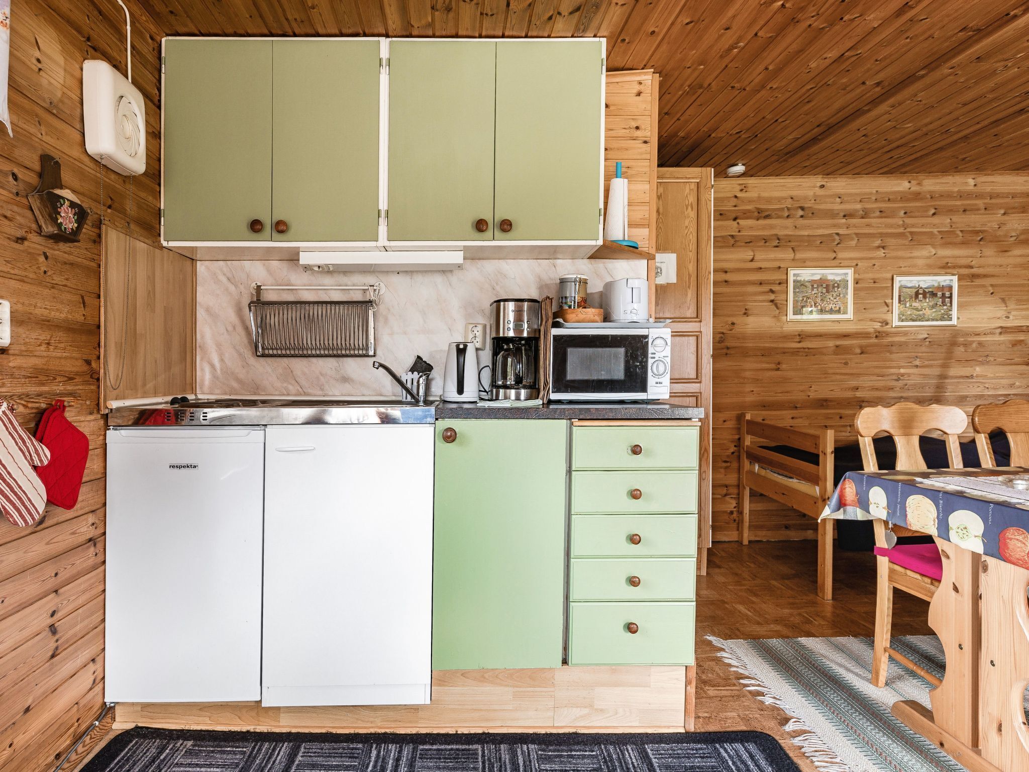 A compact kitchen with wooden cabinets, a microwave, a coffee maker, and a dishwasher.