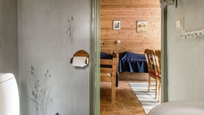 A room with a wooden floor, a bed with a blue cover, a wooden chair, and a wall-mounted towel rack. - Tingsmåla by Interhome (Tingsryd)