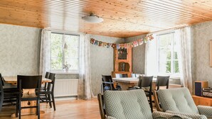 A cozy room with wooden floors, a dining table, chairs, a sofa, and a cabinet. - Gåragöl by Interhome (Olofström)