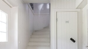 En trappa leder upp till en dörr märkt med ”WC”. Golvet är svart- och vitrutigt, och dörren är vit med ett mässingshandtag.